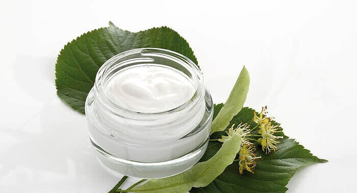 Small glass jar of cream sitting on leaves